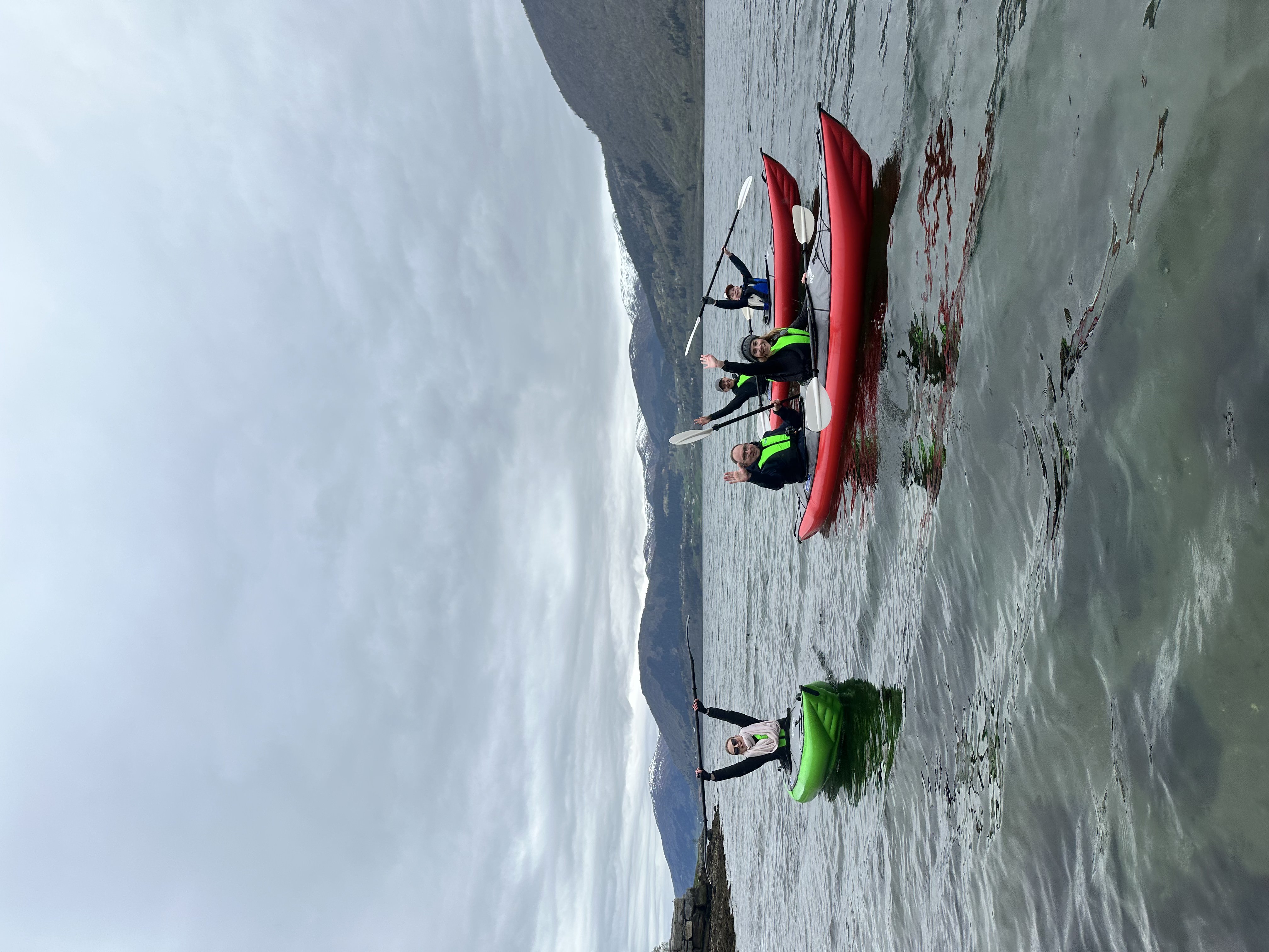 Kayaker smiling in a fjord with dramatic mountains behind